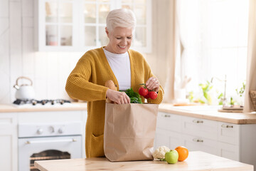 Smiling senior lady checking grocery ordered from internet