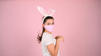 Girl in a mask with bunny ears, on a pink background
