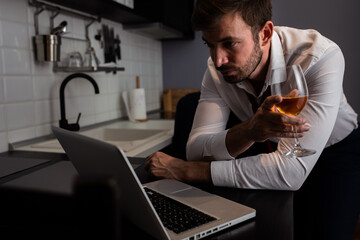 Portrait of businessman at home resting after long day at work having video call at kitchen using laptop.