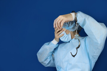 Female doctor in handcuffs covers her face, concept of medical corruption, bribery