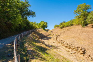 Fototapeta na wymiar The ruins of the Paved Etruscan Road in Roselle or Rusellae, an ancient Etruscan and Roman city in Tuscany. The road leads toward the centre of Roselle