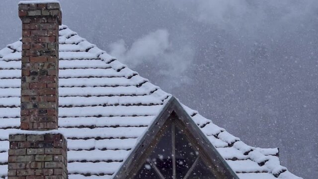 Snow Falling on the Roof tiles of the house with Smoking Chimneys.