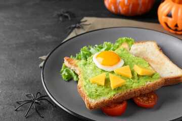Halloween themed breakfast served on black table, closeup. Tasty sandwich with fried egg