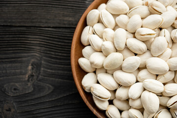 Bowl with pistachios on a wooden table. (selective focus; close-up shot)