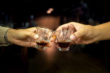 Vintage couple makes a toast with two glasses of whiskey on dark background