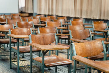 Wooden lecture chairs arranged in the classroom. Empty college classroom with many vintage wooden lecture chairs but no students. Back to school concept. 