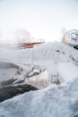 Frozen bridge covered in snow and ice over a steamy river