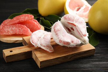 Fresh peeled pomelo fruit on black wooden table, closeup