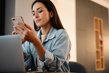 Beautiful woman using mobile phone and laptop computer