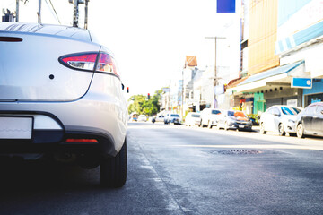closeup back of white car parked on the side of the road with soft-focus and over light in the background
