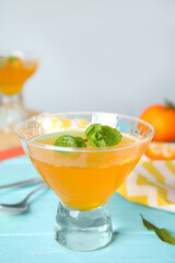 Delicious tangerine jelly on light blue wooden table, closeup