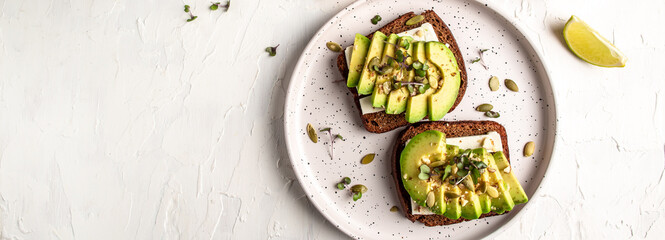 healthy toasts with avocado, cheese and whole wheat rye bread on a plate. tasty Italian meal. Long...