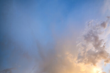 Fototapeta premium Dramatic sky at sunset with puffy clouds lit by orange setting sun.