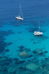 Fototapeta na wymiar Crystal clear blue water under sailing boats, near Bonifacio, Corsica, vertical photo