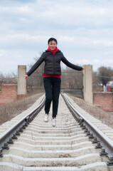 chinese woman jumping on railroad tracks