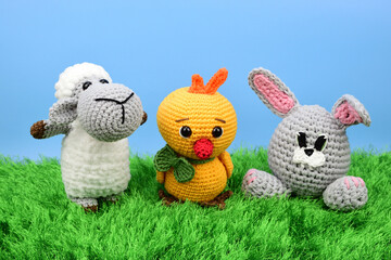 Easter symbols - lamb, chicken and rabbit standing on green grass against blue sky background