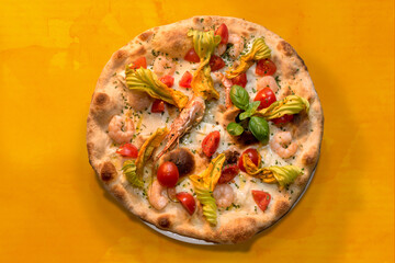 pizza with shrimps, courgette flowers, cherry tomatoes and mozzarella cheese, top view flat lay on orange watercolor background