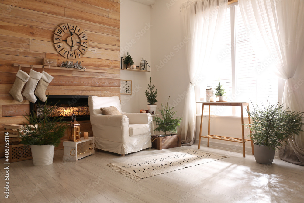 Wall mural Potted fir trees and Christmas decorations in room with fireplace. Stylish interior design