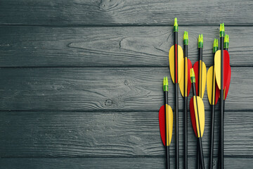 Plastic arrows and space for text on grey wooden table, flat lay. Archery sports equipment