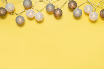 Gray white festive garland on yellow background flat lay top view. Cotton Balls Garland. Round bulbs LED festoon lights electric garland. Festive decoration Colors year 2021 Illuminating Ultimate gray