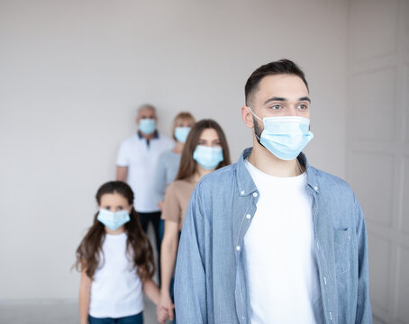 Young Caucasian Guy In Face Mask Waiting In Line For Coronavirus Vaccination At Health Centre, Copy Space