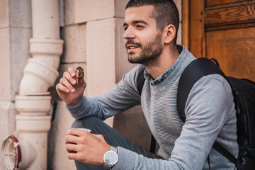 Obraz premium Young urban man on break from work drinking coffee and eating cookie 