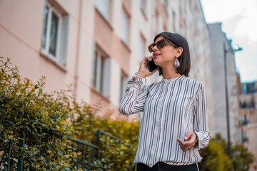 Young urban business woman talking on phone on city street 