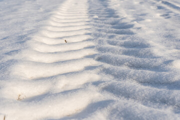 Fototapeta na wymiar footprints of a large tractor tire in white snow