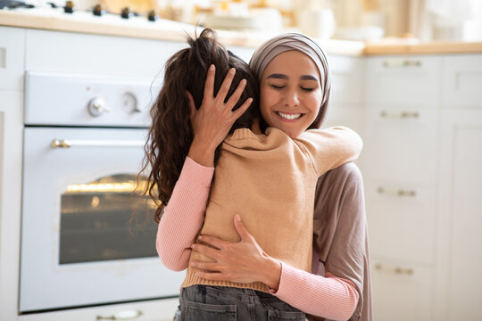 Happy Mother's Day. Little Girl Cuddling Tight Her Muslim Mom In Kitchen