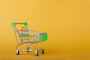 Empty supermarket shopping grocery cart on colored background