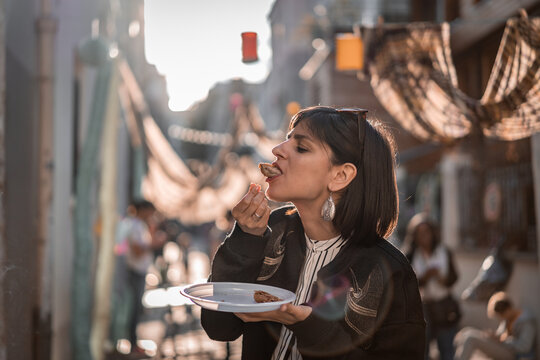 Beautiful young female tourist in city of Paris France enjoying holidays in beautiful little street festival eating street food