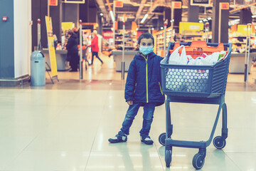 Boy wears protected mask in store. Shopping time during coronavirus outbreak. Boy in a medical mask. Shopping with kids during virus outbreak. Boy in face mask in supermarket. toned