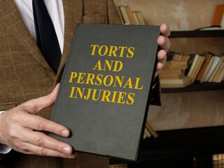 Hands holding a book Torts and Personal Injuries law book.