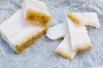 Raw pork fat with meat on white parchment for copy space. A large chunk of fresh fat. Ukrainian lard. Sliced ​​pieces of bacon. Ukrainian traditional food.
