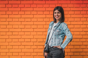 Attractive young woman posing on a background of a red colorful brick wall. Empty space for text o design.