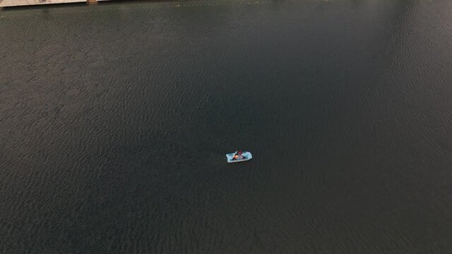 Aerial shot of people in a paddle boat on a green lake-