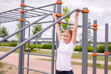 A teenage girl in sports uniform practicing on the playground in warm weather