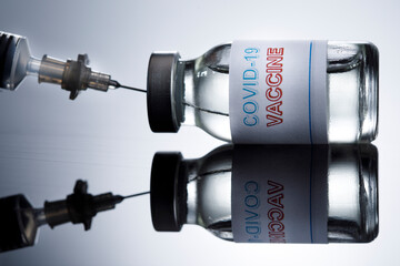 prelievo del  vaccino anti-covid con una siringa da una filetta di vetro, isolato su sfondo bianco riflettente