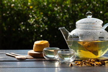 Chrysanthemum tea in glass kettle with cup and scone for afternoon tea party in garden