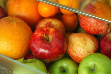 Organic apples and citrus fruits in a container from a fridge