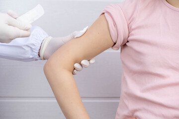 the doctor made an injection into the child's hand, squeezed the injection site with a cotton swab and wants to apply a plaster