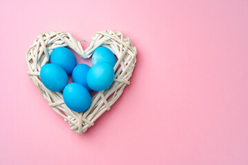 Painted Easter eggs in decorative nest on pink background