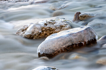 Ice covered rocks laying in shallow brook