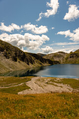 Fanealm und Wilder See in Suedtirol, Italy, Alpine pastures with a deep blue lake, green meadows and a blue sky with fleecy clouds, in summer