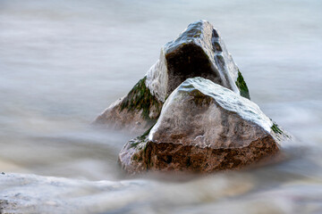 Ice covered rocks laying in shallow brook