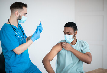 Covid-19 vaccination program. Black male patient getting coronavirus vaccine shot on visit to...