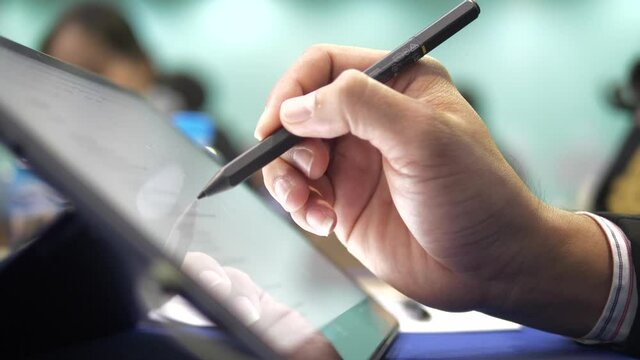 Close up hand using digital pen on tablet screen for design or note taking, modern technology and smart learning concept