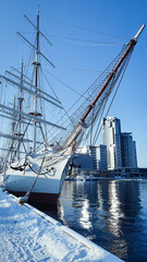 Sailing ship at the snow-covered quay in the Polish city of Gdynia. A skyscraper in the background....