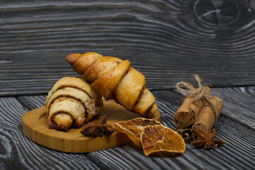 Cinnamon and poppy seed buns. Rich pastries. Nearby are cinnamon sticks, anise and dried oranges. Close-up shot.