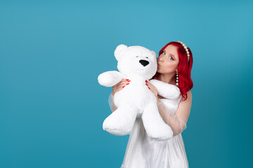 mock up of a beautiful woman hugging a large white teddy bear and kissing it on the cheek, isolated on a blue background.